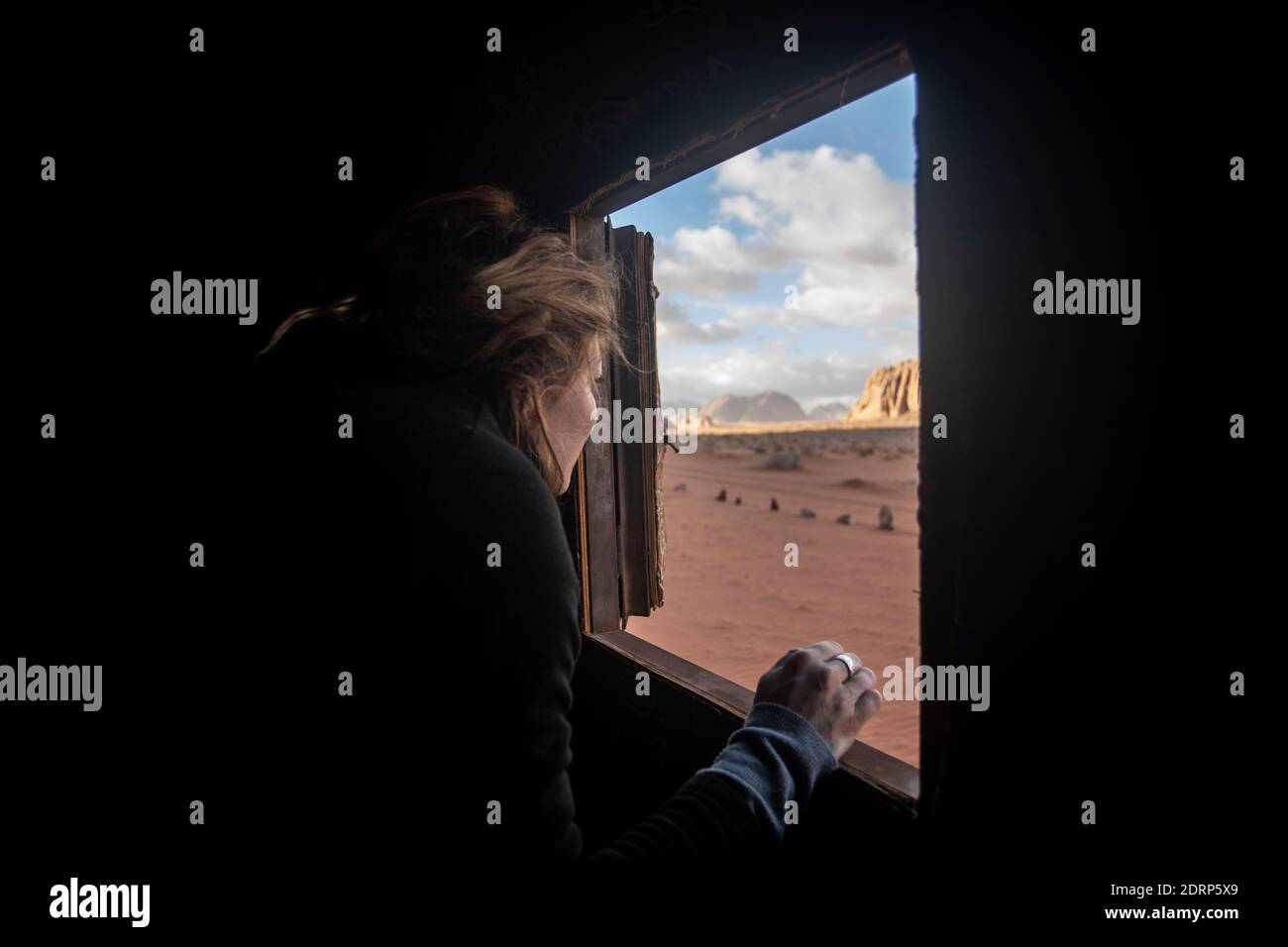 A turist is looking out the window of her small tent in Wadi Rum Desert, Jordan, feb 2020, few weeks before the global lockdown. Stock Photo