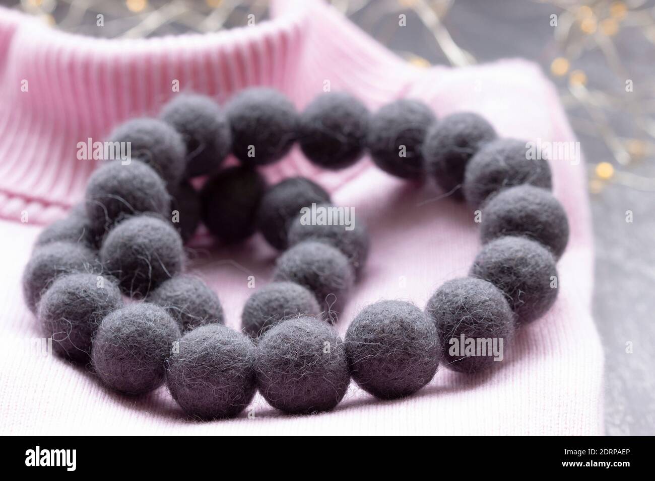 Handmade wool necklace on the background of clothes. Stock Photo