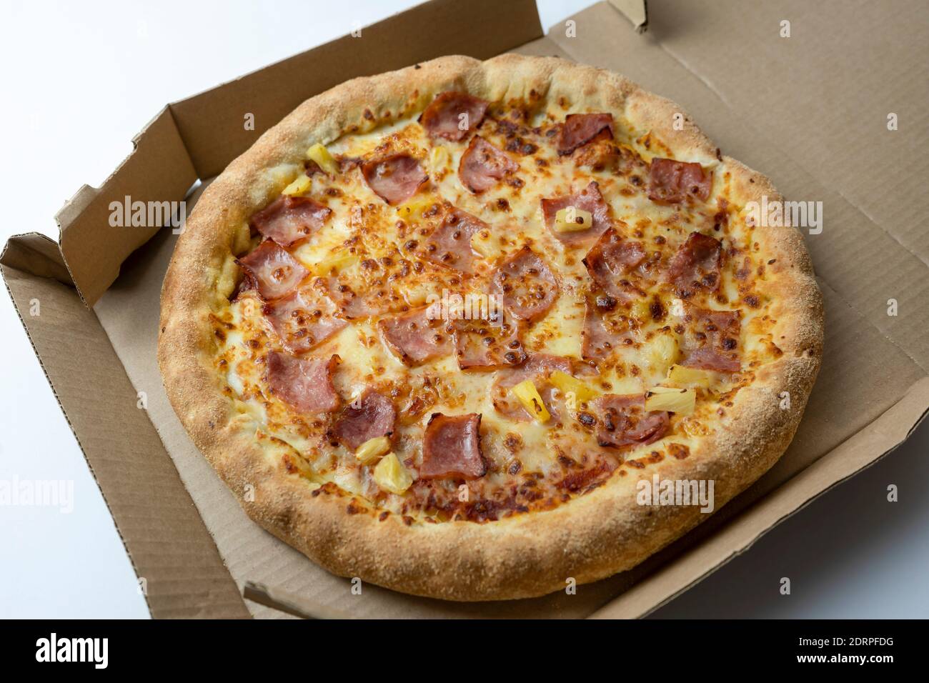 Hawaiian Pizza with bacon , cheese and pineapple on cardboard box