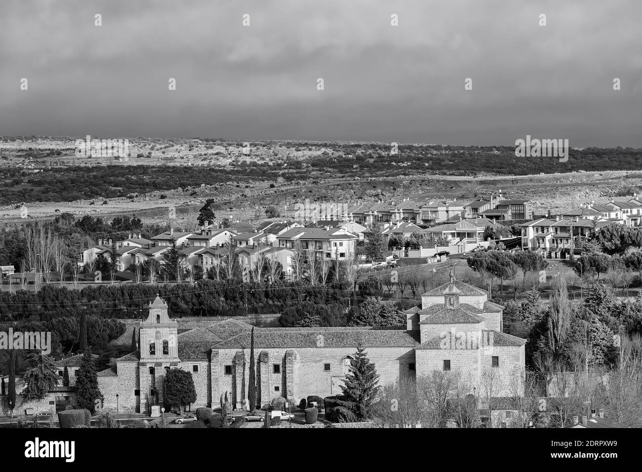 A grayscale shot of the Avila cityscape with the Monastery of the Incarnation in the foreground Stock Photo