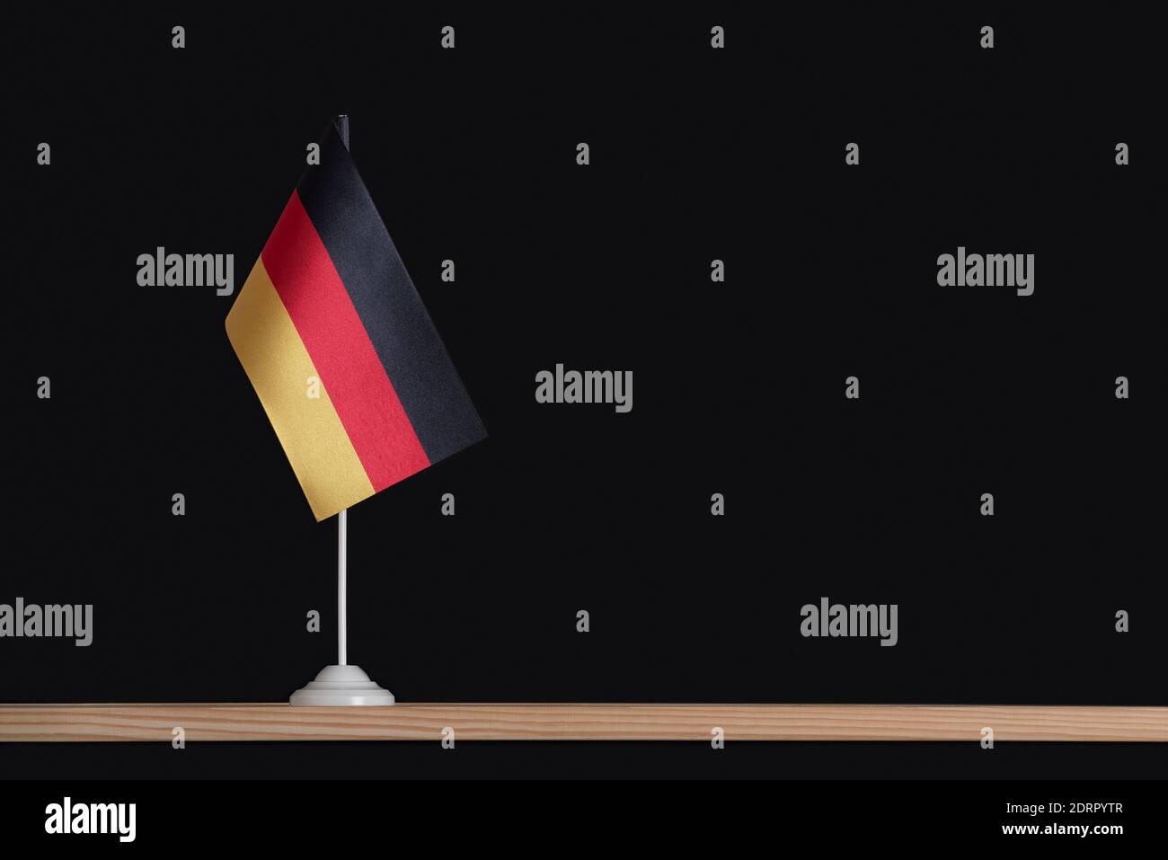 National flag of Germany on table, black background. Tricolor flag of