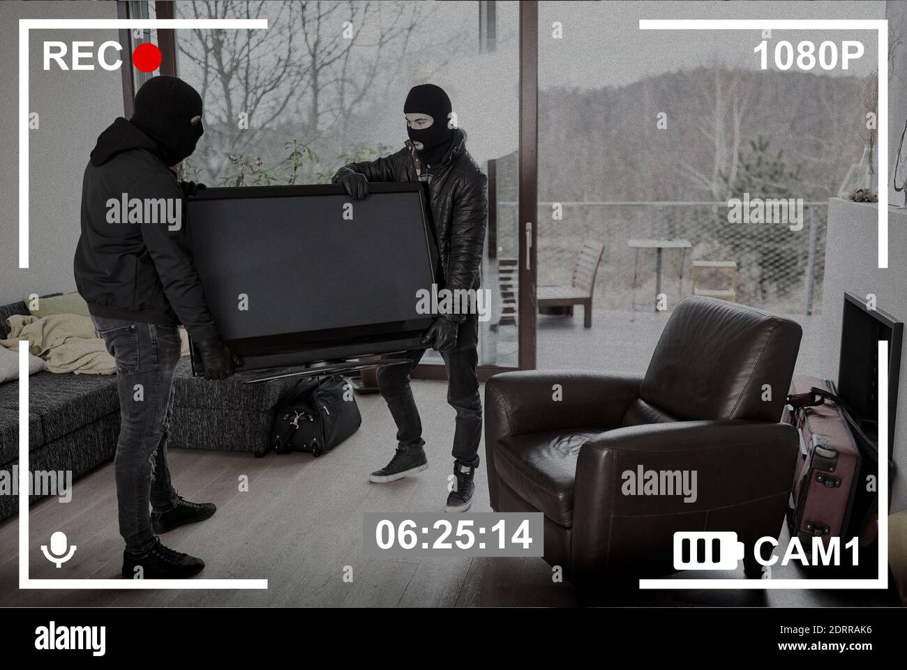 Surveillance camera records two intruders stealing a large TV from the living room Stock Photo