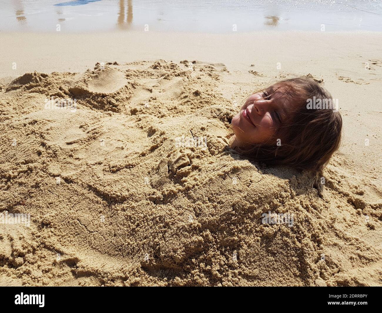 Girl buried in sand hi-res stock photography and images - Alamy