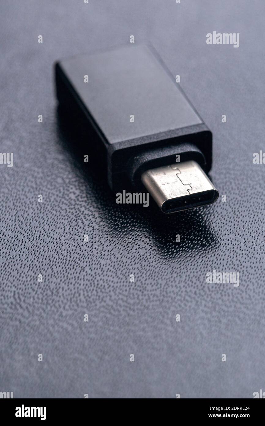 Black USB OTG (USB on The Go) with USB Type C port for connection betwen cellphone and flash disk drive on black background Stock Photo