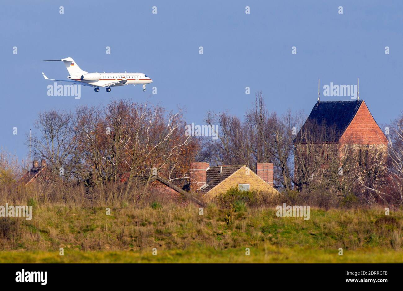 14 December 2020, Brandenburg, Schönefeld/Ot Selchow: A twin-engine Bombardier BD-700-1A10 Global 6000 with the registration 14-07 and the inscription 'Federal Republic of Germany' is approaching BER above the houses of the village. Photo: Soeren Stache/dpa-Zentralbild/ZB Stock Photo