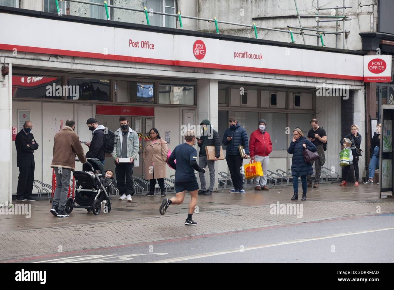 Clapham, London, 21 December 2020: People form a socially distanced queue at the Post Office in Clapham. Many people in Tier 4 are no longer able to visit relatives or form a Christmas social bubble and so will be posting parcels of presents to loved ones. Anna Watson/Alamy Live News Stock Photo