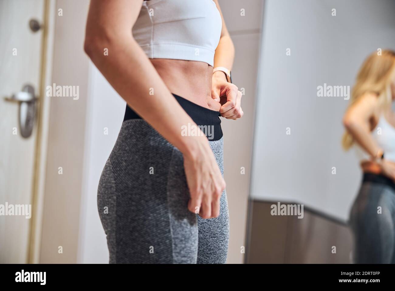 Elegant pretty woman standing in front of the mirror while holding skin in home Stock Photo