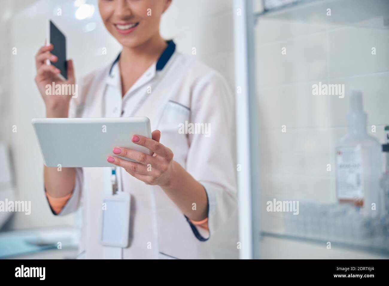 Smiling female dentist using gadgets in office Stock Photo
