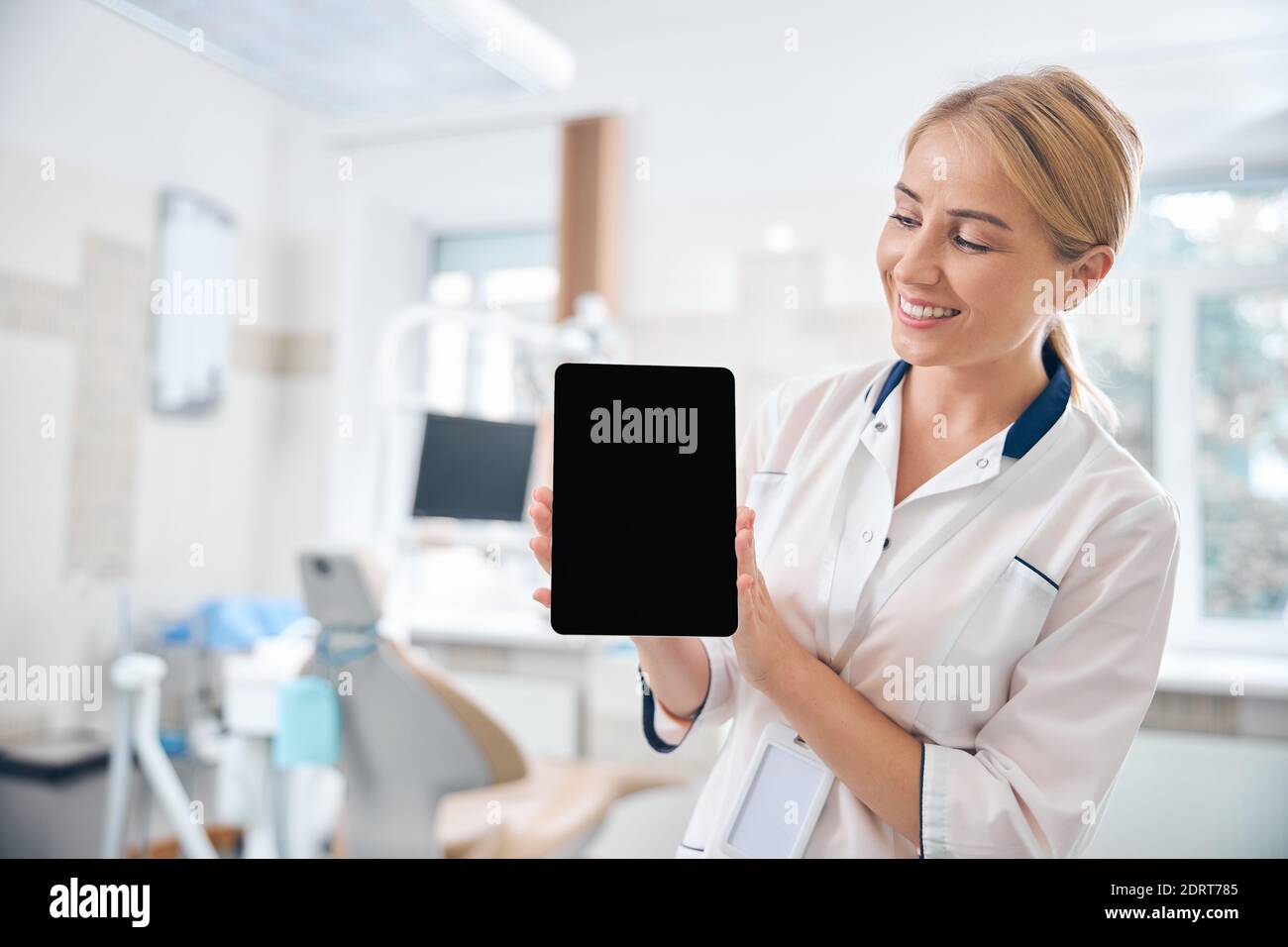 Happy female dentist using tablet at work Stock Photo