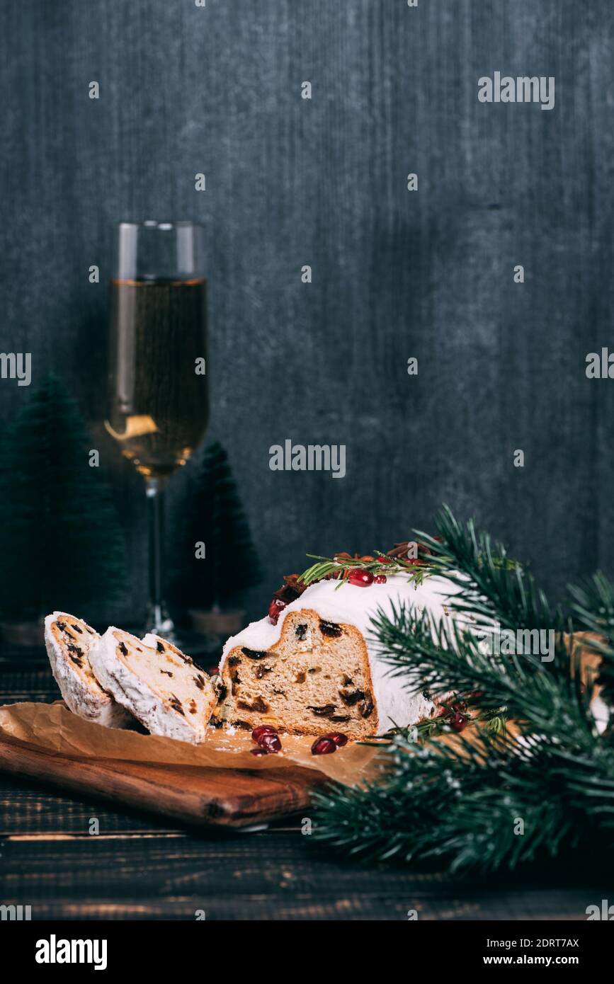 Christmas fruit cake with sugar powder and glass of champagne on marble board. Wooden table and copy space for your text Stock Photo