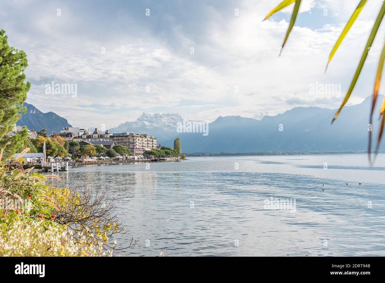 Alpine lake shore surrounded by snowy peaks and a town in the shore. Montreux, Lake Geneva in Switzerland Stock Photo