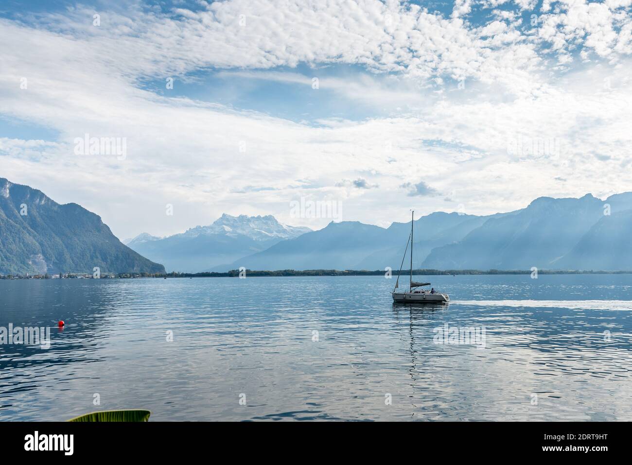 Alpine lake with the calm water with a boat sailing surrounded by snowy peaks. Montreux in Geneve lake Stock Photo
