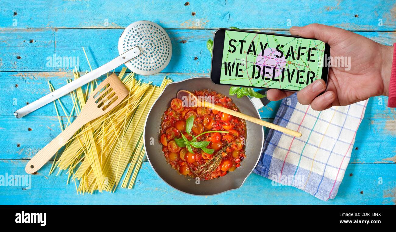 COVID-19 'STAY SAFE WE DELIVER' Coronavirus social distancing restaurant business smartohone with text offering online food delivery Stock Photo