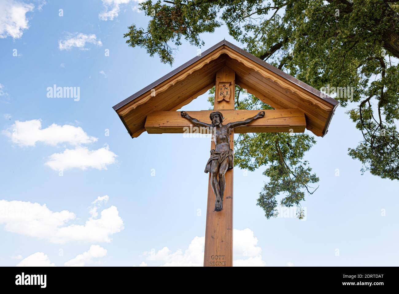 Corridor cross with Jesus in front of blue cloudz sky and branches - Calvary Stock Photo