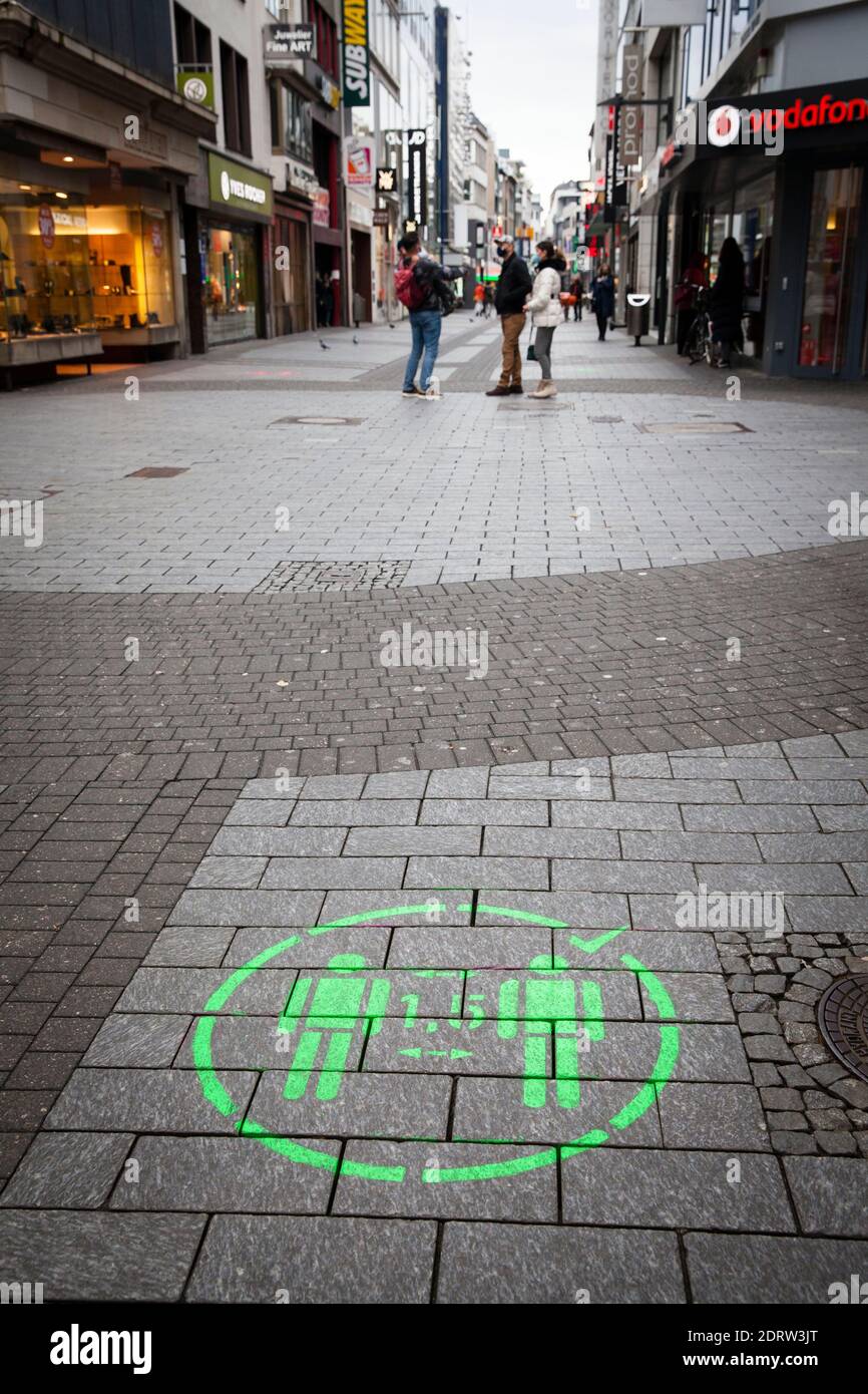 Corona Lockdown, December 16th. 2020. Only few people on shopping street Hohe Strasse, usually visited by thousands of people, logo keep distance, Col Stock Photo