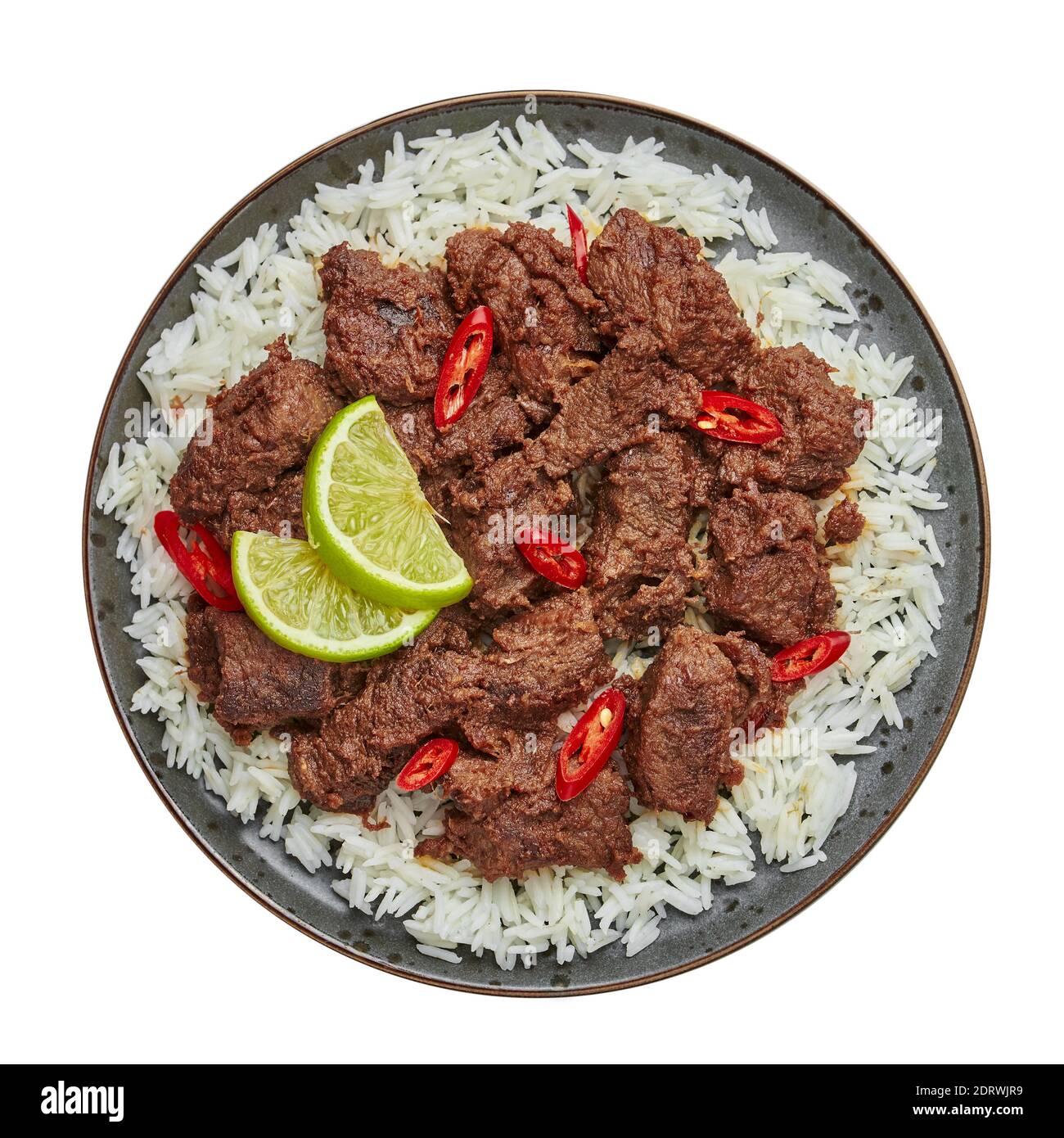 Beef Rendang on black plate isolated on white. Indonesian padang cuisine meat dish. Asian food. Top view Stock Photo