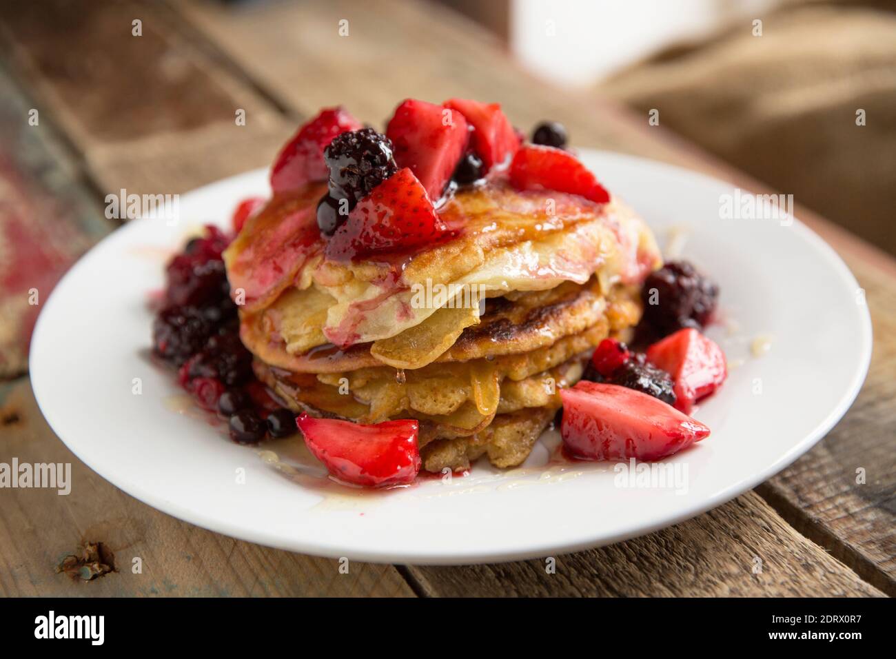 Homemade American style pancakes served with honey and defrosted frozen fruit. England UK GB Stock Photo