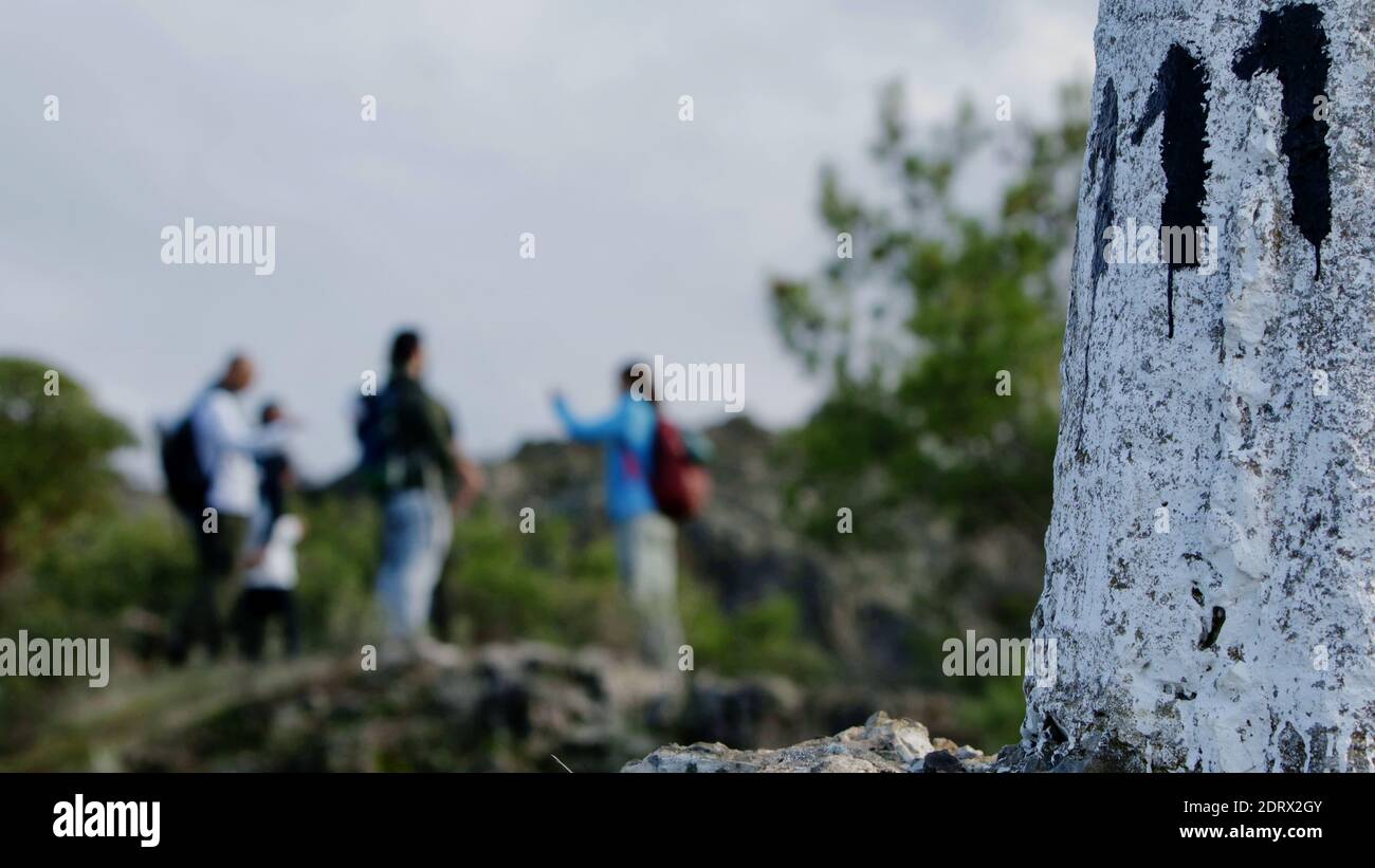 Team of hikers chatting upon arriving at the top of a hiking trail - right next to a concrete made pole with the number 111 on it Stock Photo