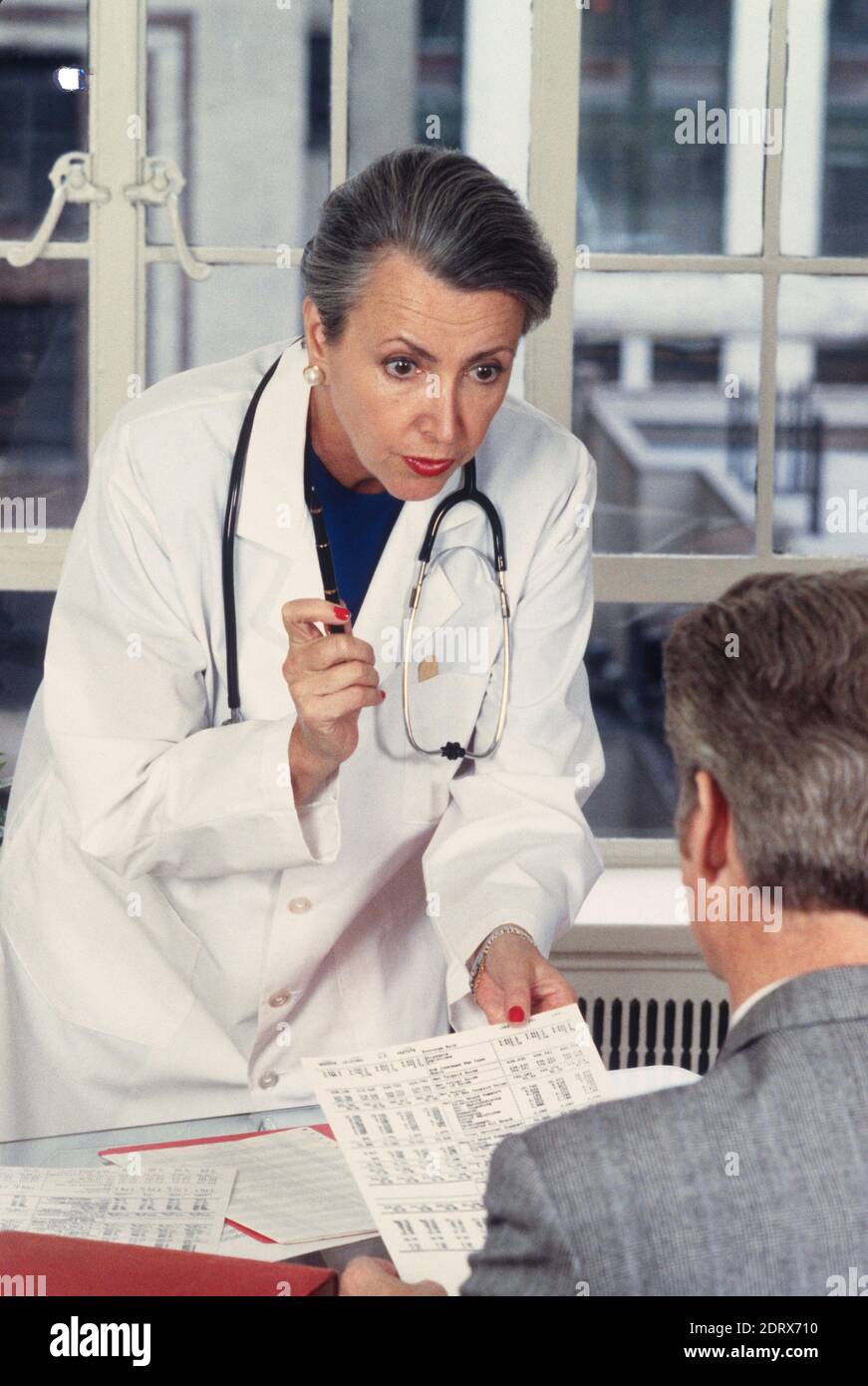 1994, Female Doctor Reviews Lab Results with a Male Patient., USA Stock Photo