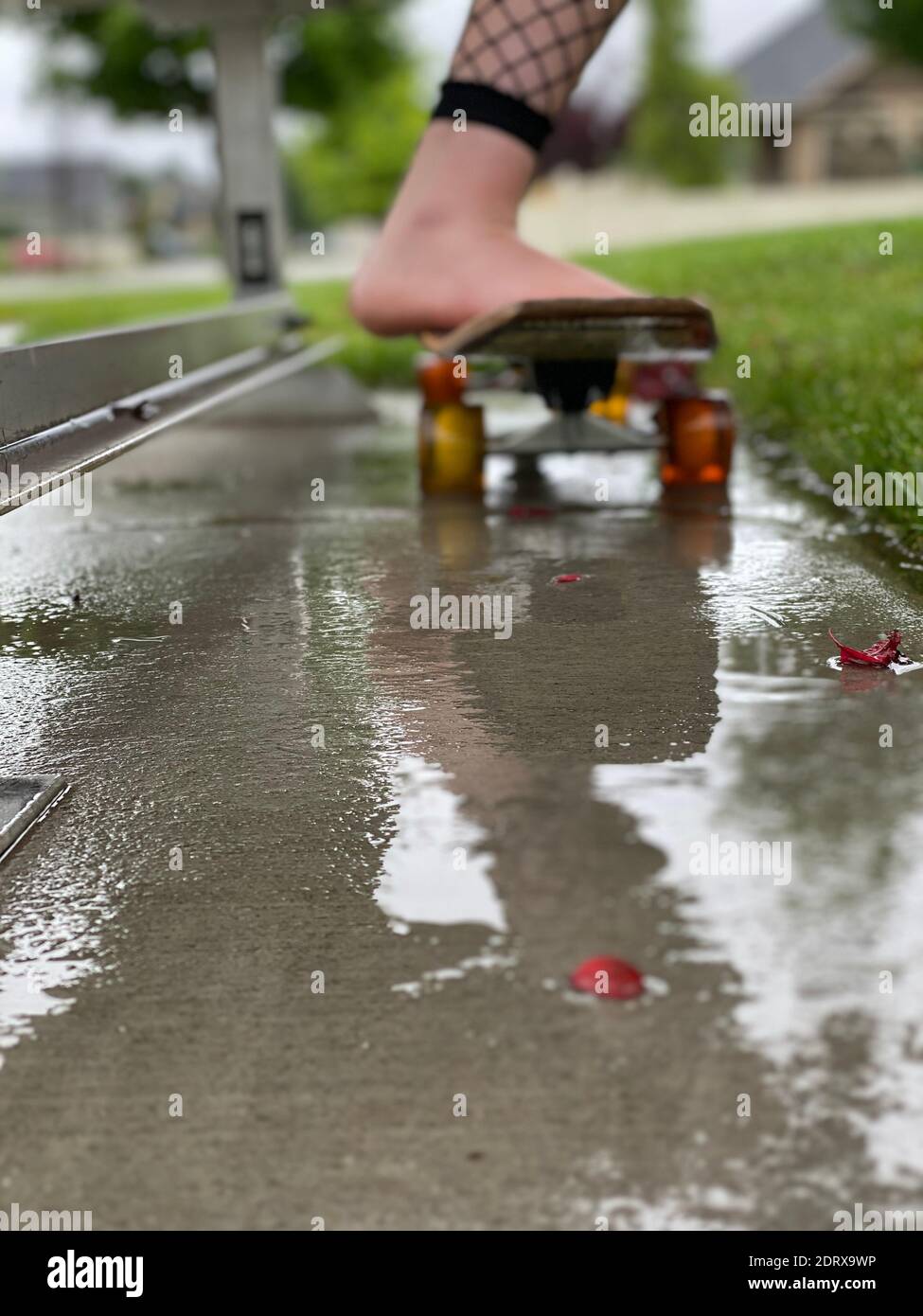 Skater Life, Rainy Day, Feet Resting On Skateboard In The Rain, Reflection  On Wet Ground Stock Photo - Alamy