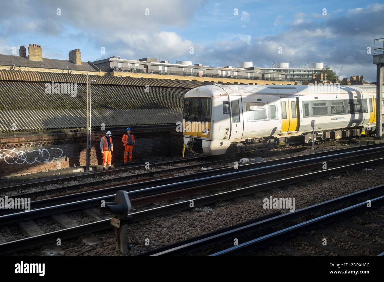 Rail workers stand safely at the trackside next to a commuter train outside Victoria Station, on 5th December 2020, in London, England. Stock Photo