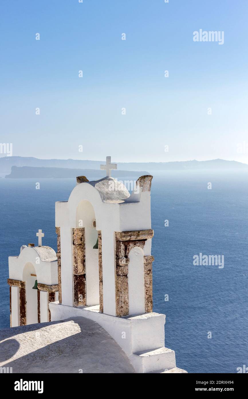 Belfries of a Greek Orthodox church gazing the deep blue of the Aegean Sea, in Oia village, Santorini island, Aegean Sea, Greece, Europe Stock Photo