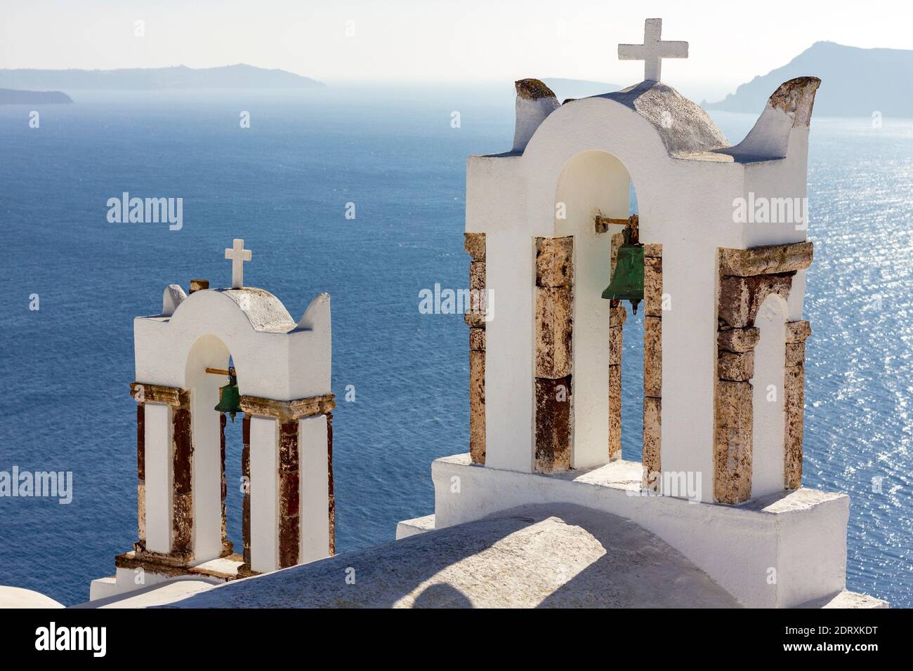 Belfries of a Greek Orthodox church gazing the deep blue of the Aegean Sea, in Oia village, Santorini island, Aegean Sea, Greece, Europe Stock Photo