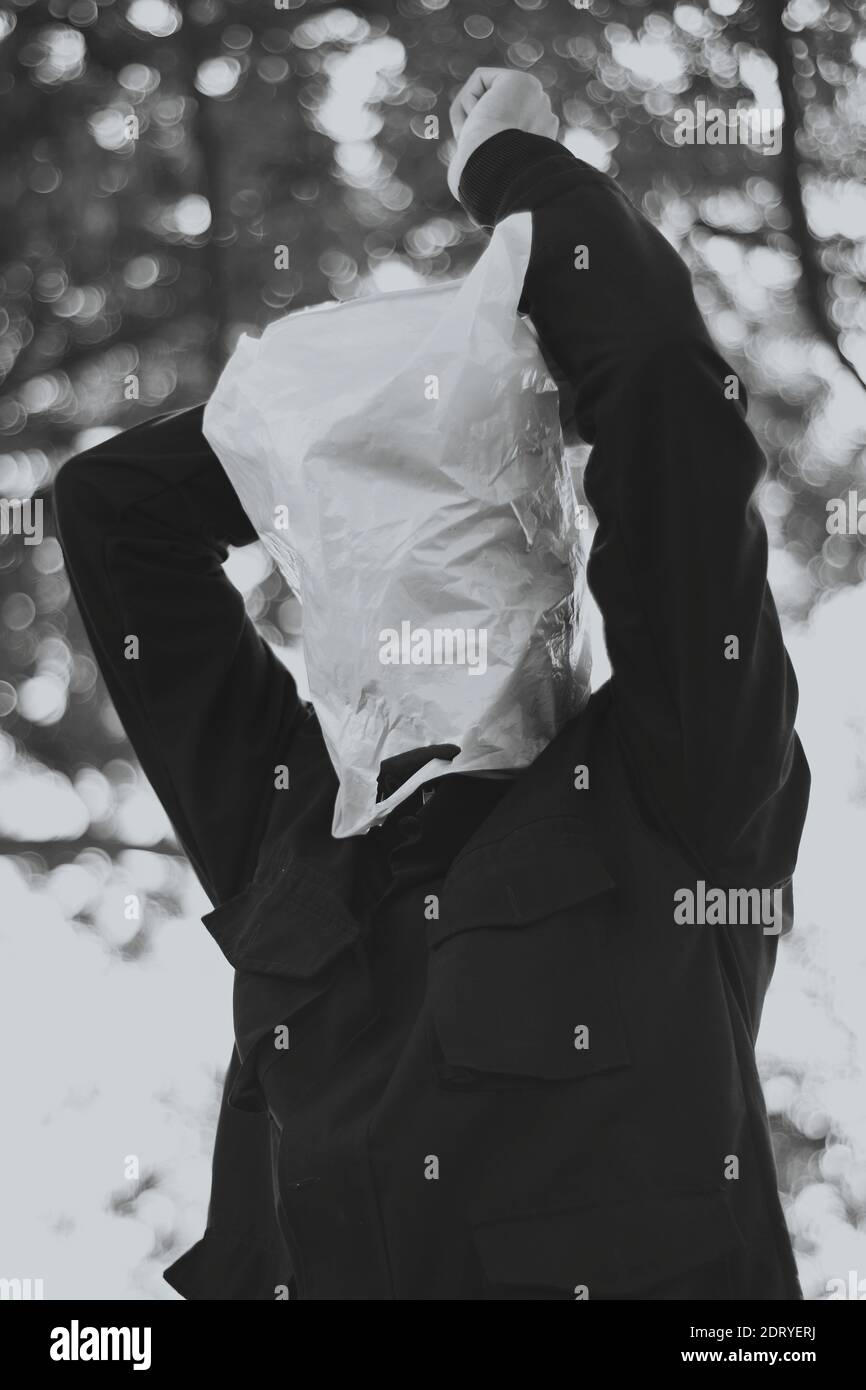 Man Wearing Plastic Bag Over Face While Standing Against Tree Stock