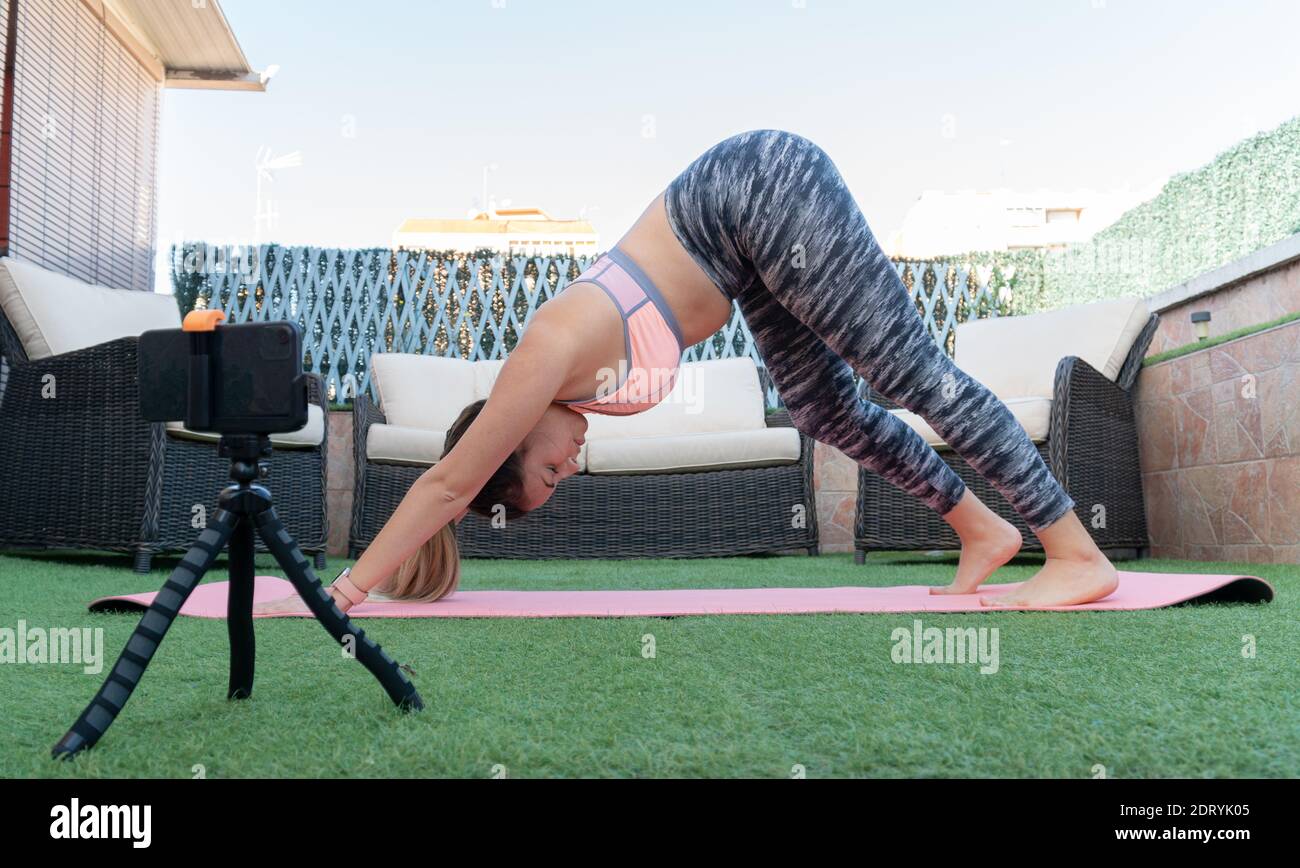 Young yoga teacher recording an online class with her mobile phone in the  garden of her house. She is doing the dog downward posture, also known as  "A Stock Photo - Alamy