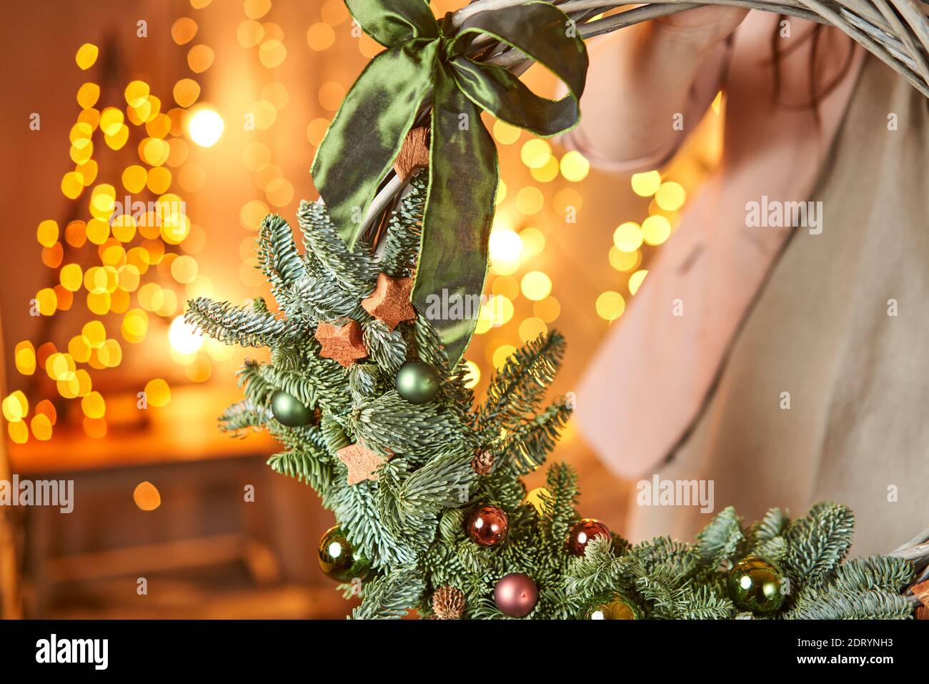 Young woman holding a Christmas wreath loop decorated fir branches and christmas toys for the holiday. The new year celebration. European flower shop Stock Photo