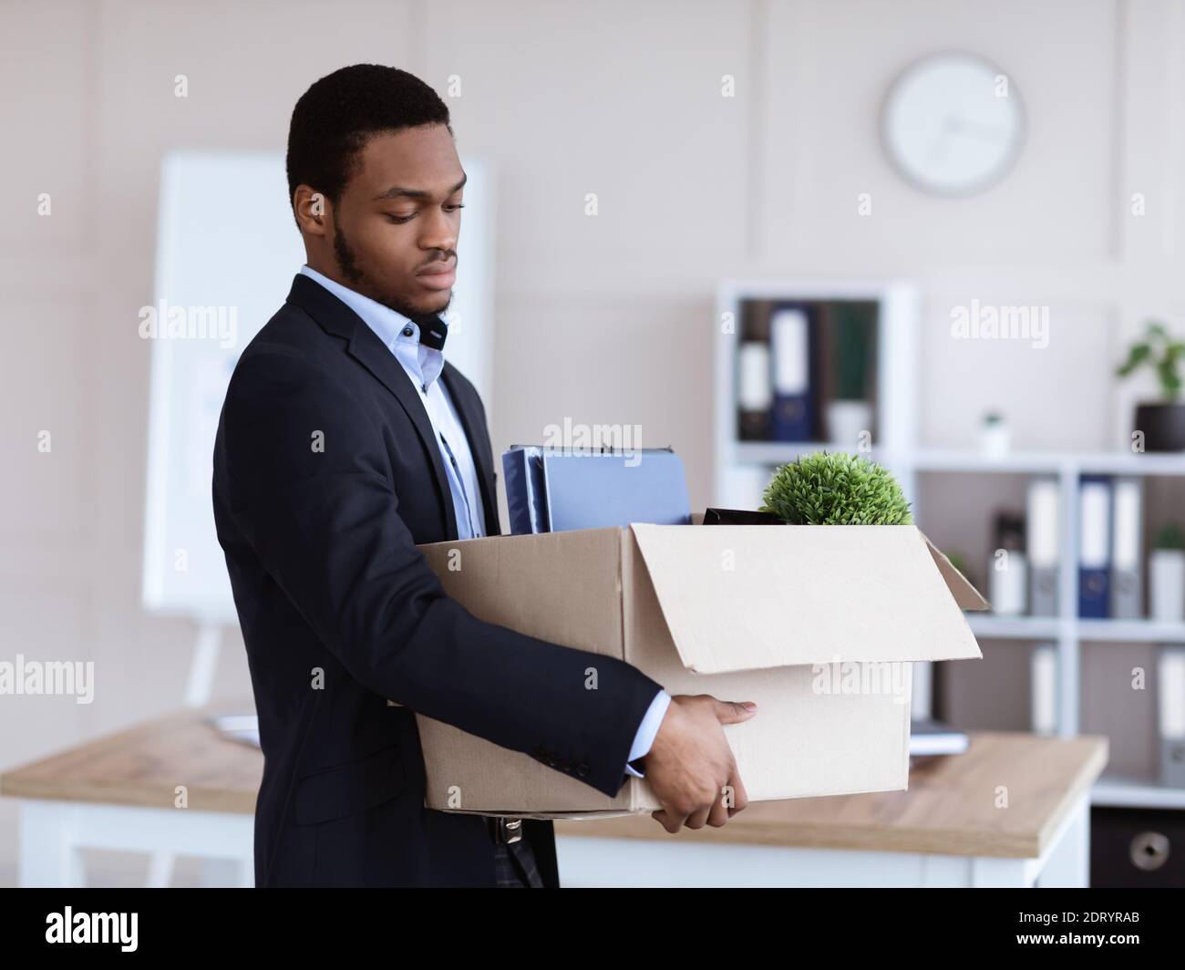 Upset black man got fired, holding box with his belongings Stock Photo