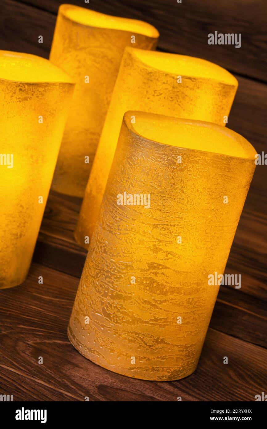 Four golden LED wax candles against wooden background Stock Photo