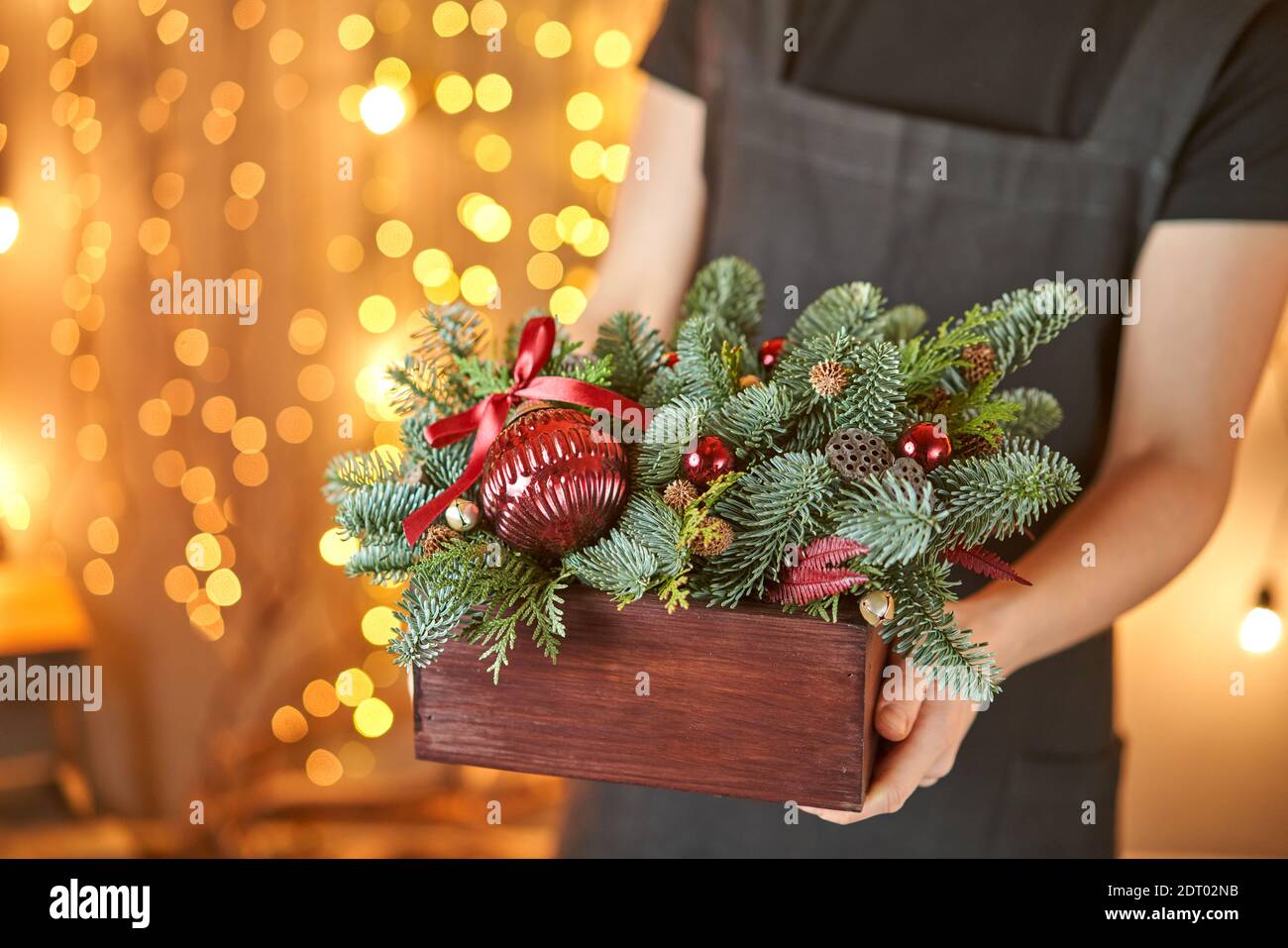 Young woman holding a Christmas wooden box with fir branches for the holiday. The new year celebration. European flower shop Stock Photo