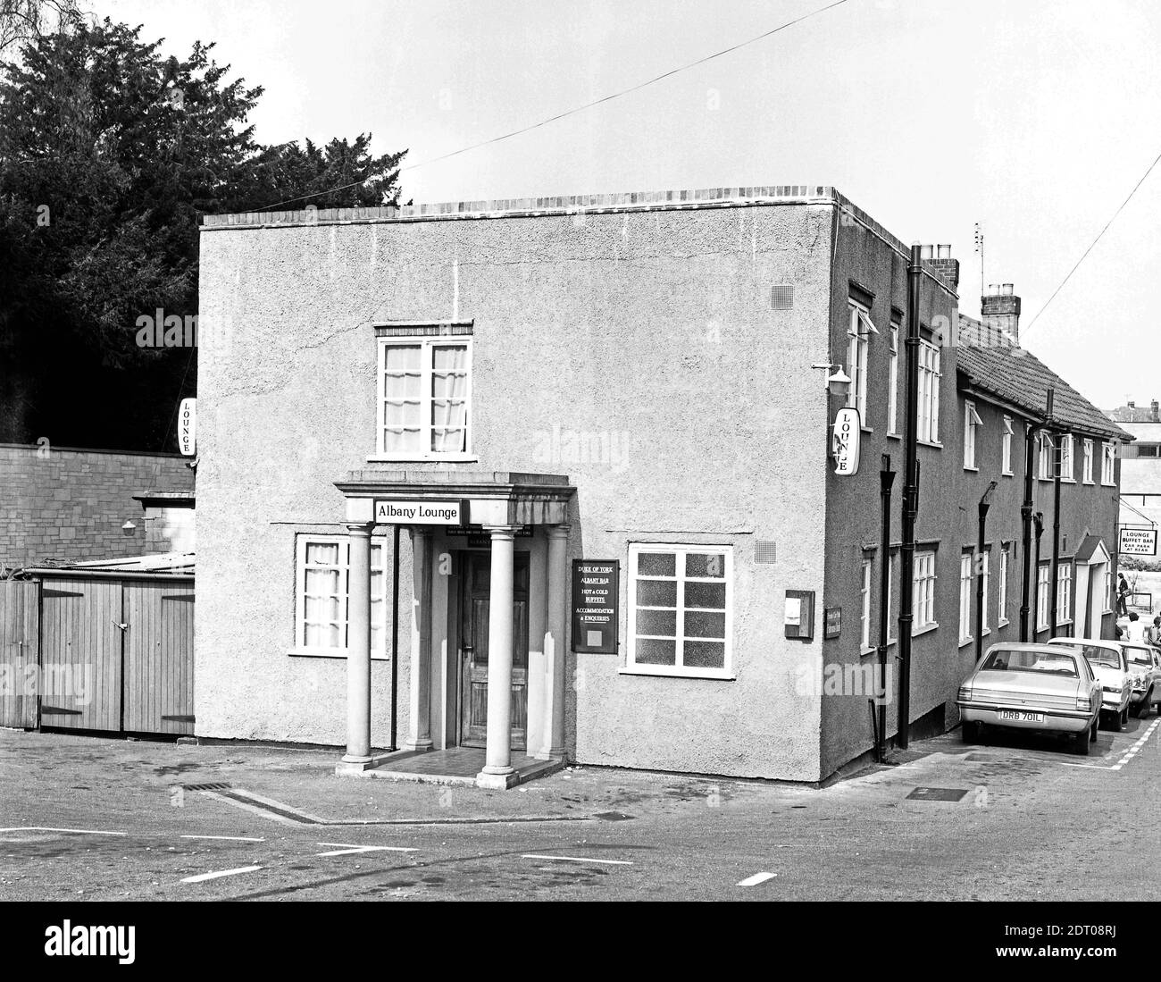 The Duke of York pub in Kingston, Yeovil. Photo taken in 1973. The main pub (see photos b and c) on the main road, was rebuilt in 1905 but this later rear elevation is more box-like. The sign over the door is for The Albany Lounge whereas the menu board advertises the Albany Bar and the perspex hanging sign has been smashed. The gallows sign on the front corner is for 'Lounge, Buffet Bar Car Park at Rear.' There is no brewery signage visible however photos c and d (maybe taken later as on 35mm negatives) show a Bass gallows sign. The nearest car is a Cortina, registration DRB 701L. No0085 Stock Photo