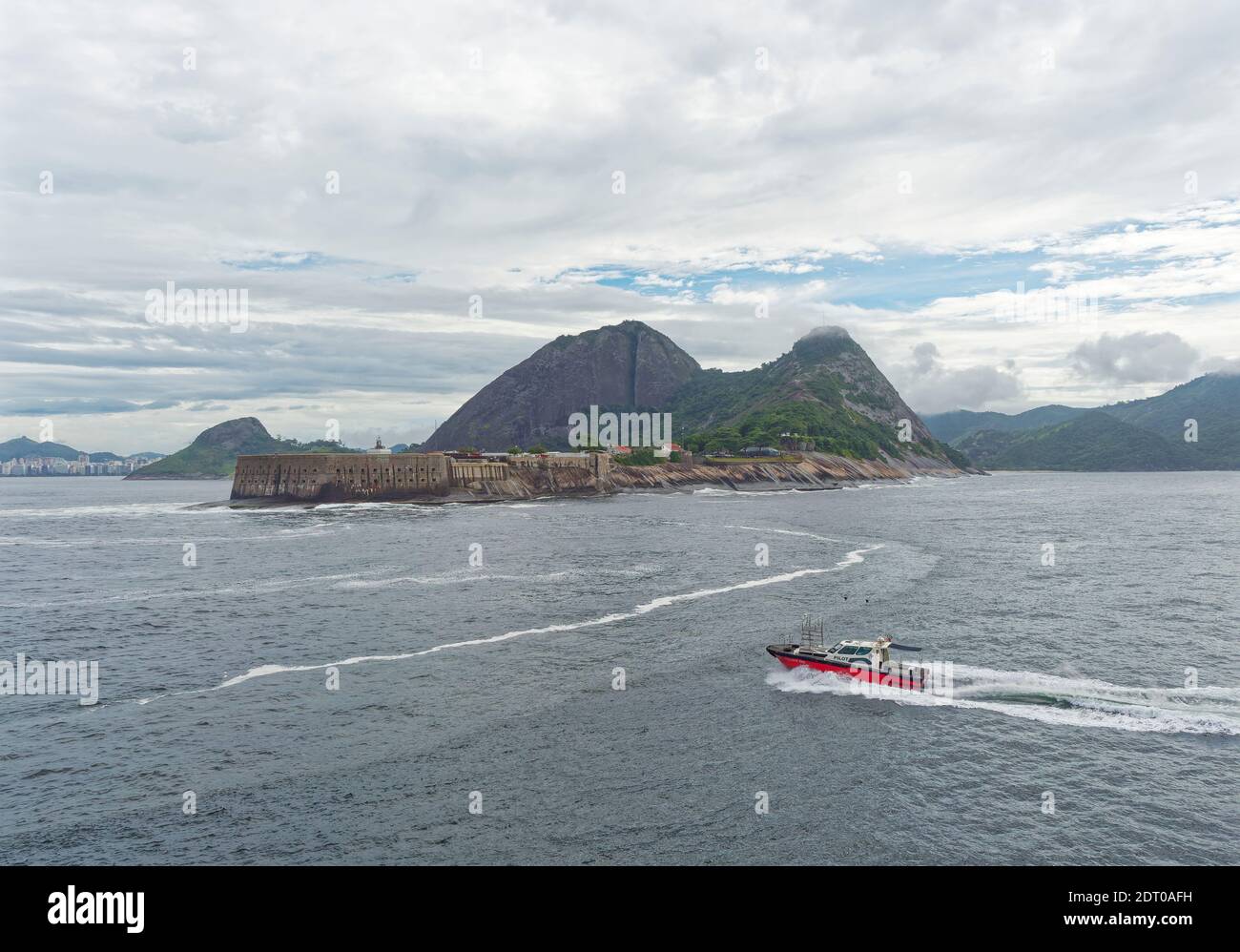 The Rio Pilot Boat heading out to another Vessel in the Anchorage, and passing by the Copacabana Fort, with the Pedra da Gavea in the background. Stock Photo