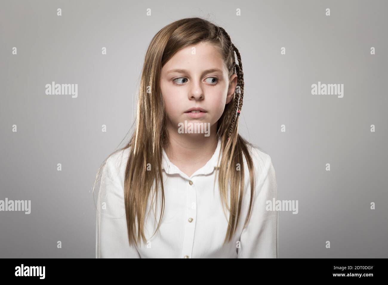 Studio portrait of a cute girl with long blonde hair looking askance against neutral background Stock Photo