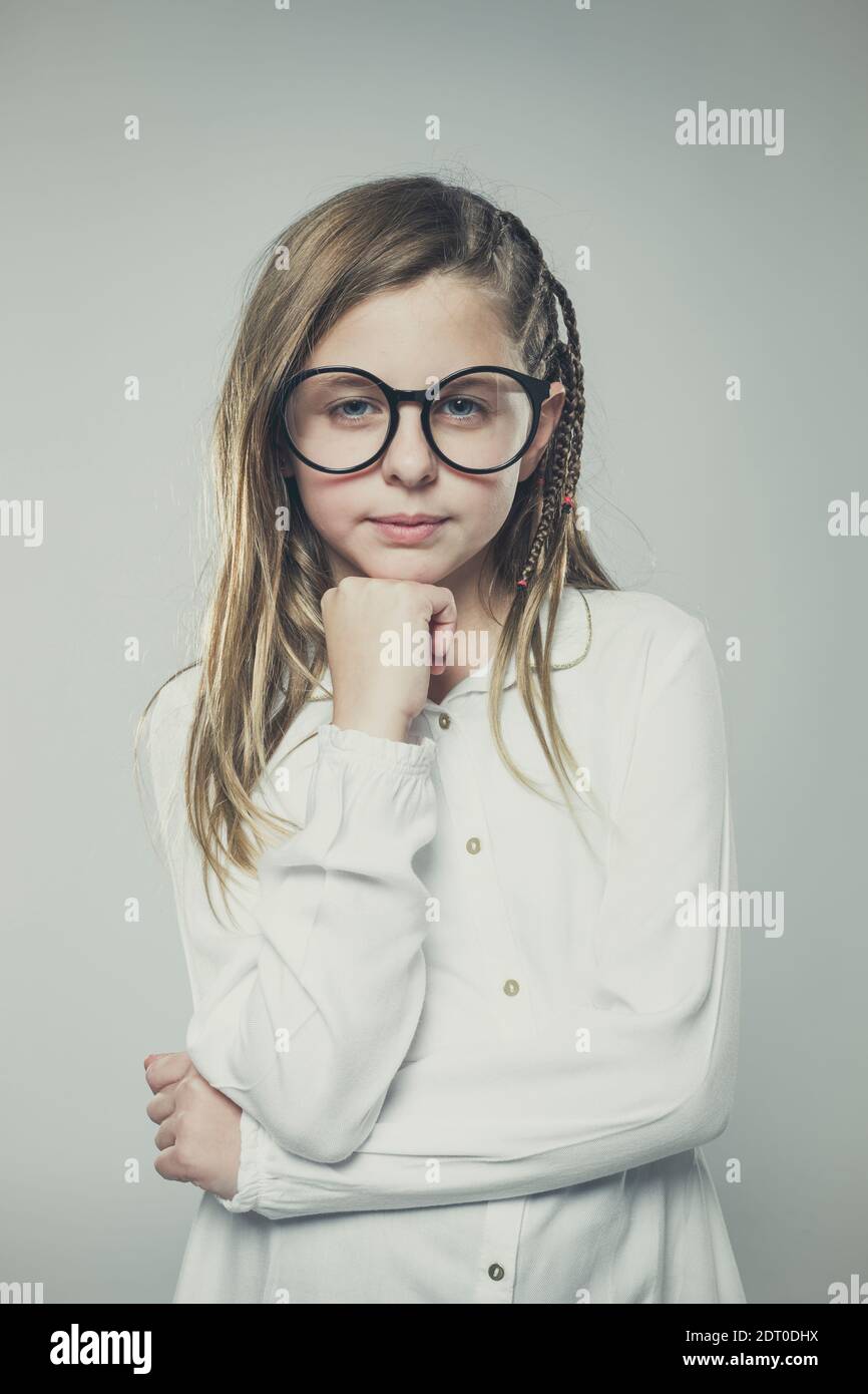 Studio portrait of a cute girl with long blonde hair wearing glasses ...