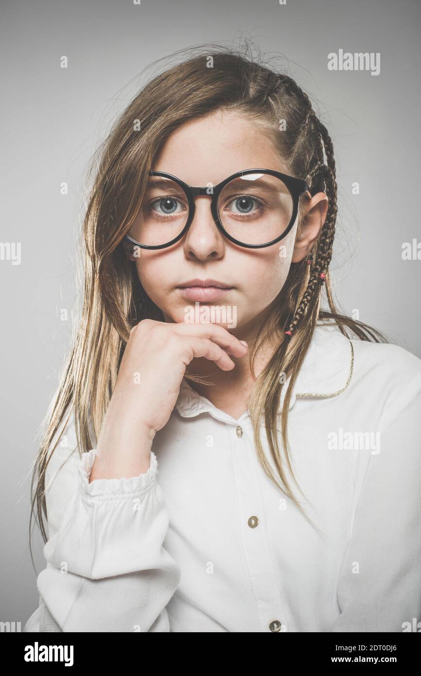 Studio portrait of a cute girl with long blonde hair wearing glasses ...