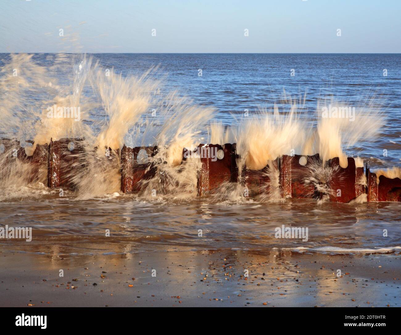 A study in motion of waves striking the remains of old sea defences at Cart Gap, Happisburgh, Norfolk, England, United Kingdom. Stock Photo