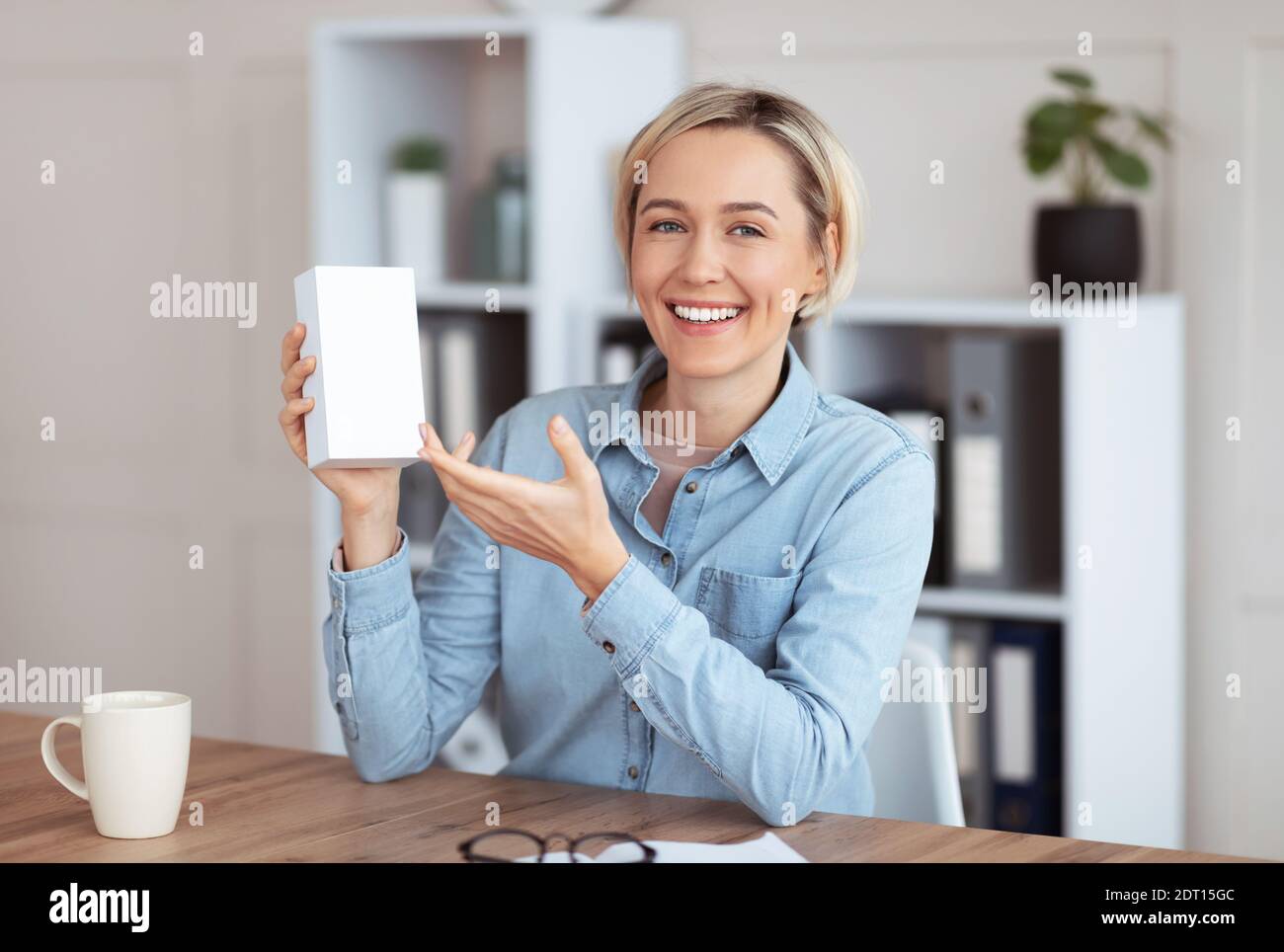Young female blogger recording video review of new device, demonstrating tech product at home, mockup for design Stock Photo