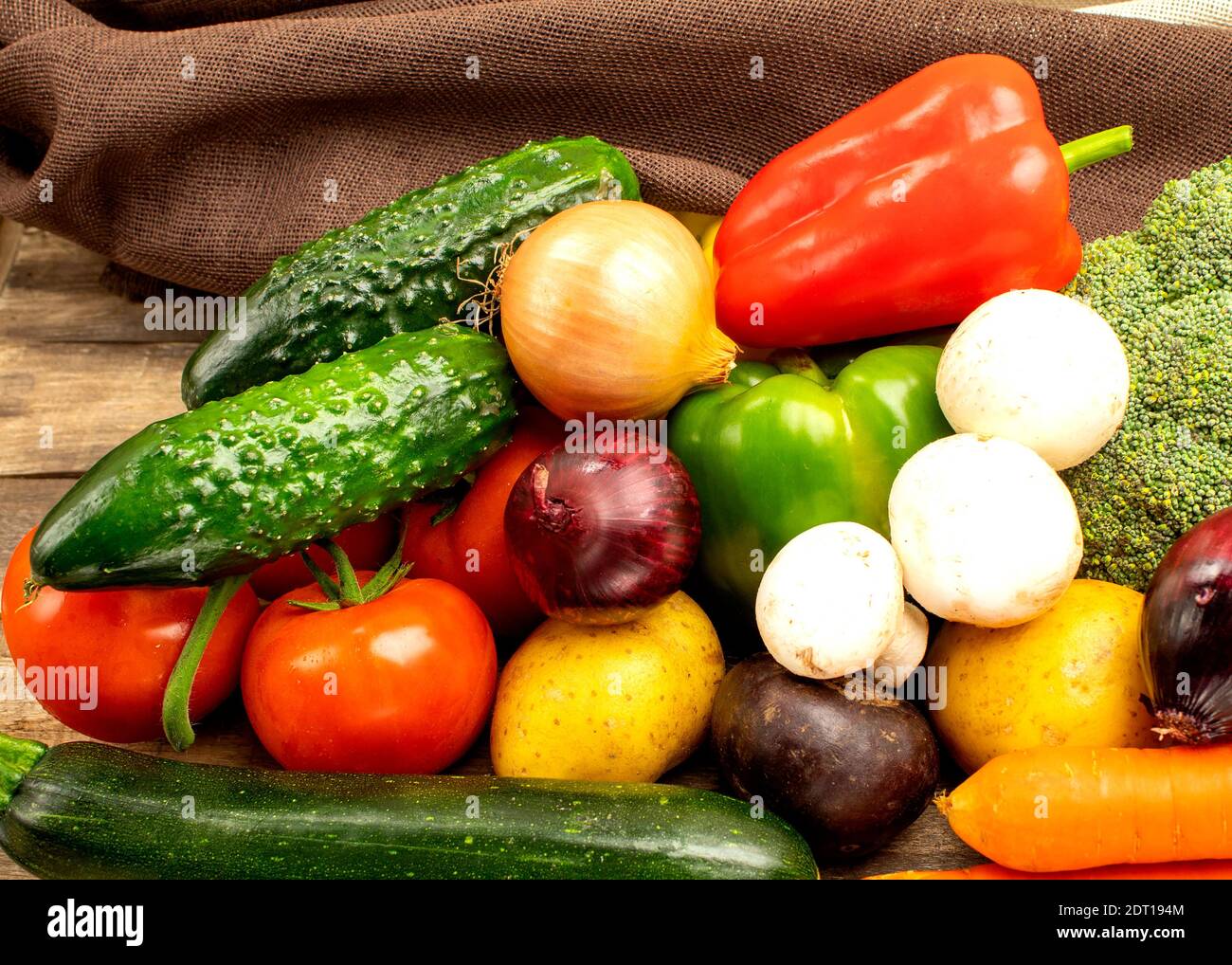 Fresh vegetables on wooden background, side view. Homemade vegetables carrots, blue onions, mushrooms, cucumber, paprika, tomato Stock Photo