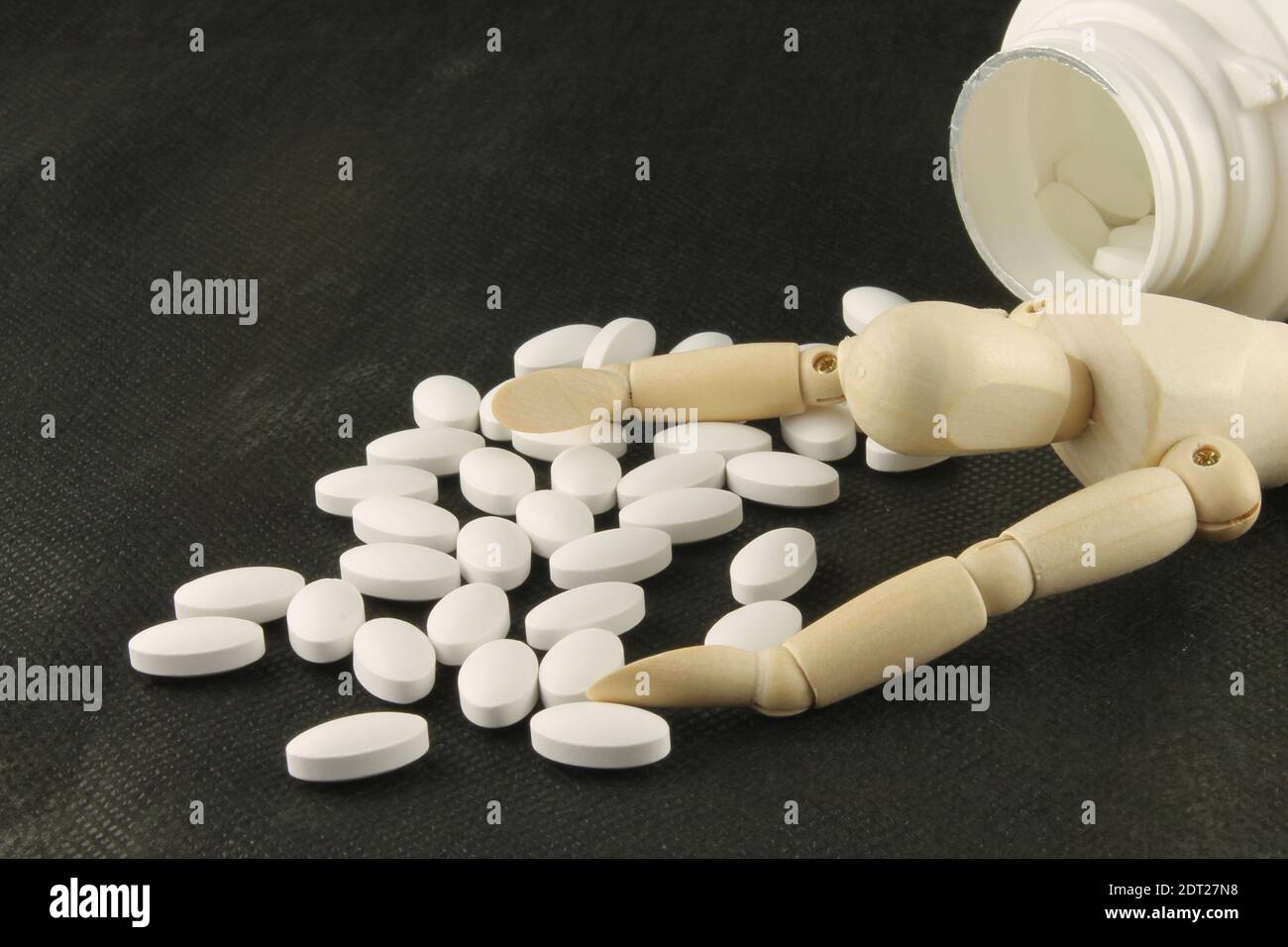 Manikin lying down with hands outstretched surrounded by white tablets on black background, Overdose prescription medication concept with copy space Stock Photo