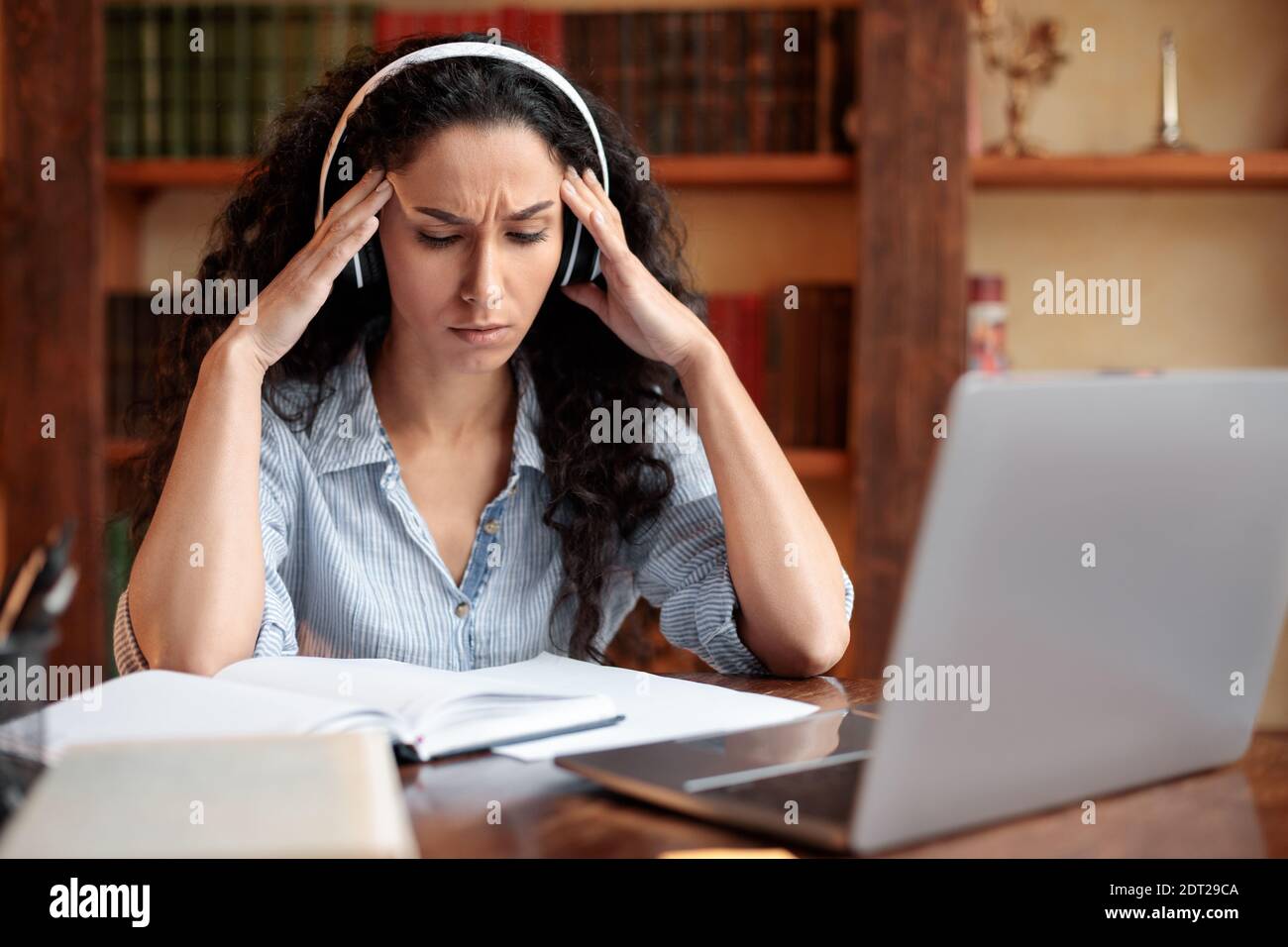 Tired woman massaging temples sitting at desk with laptop Stock Photo ...