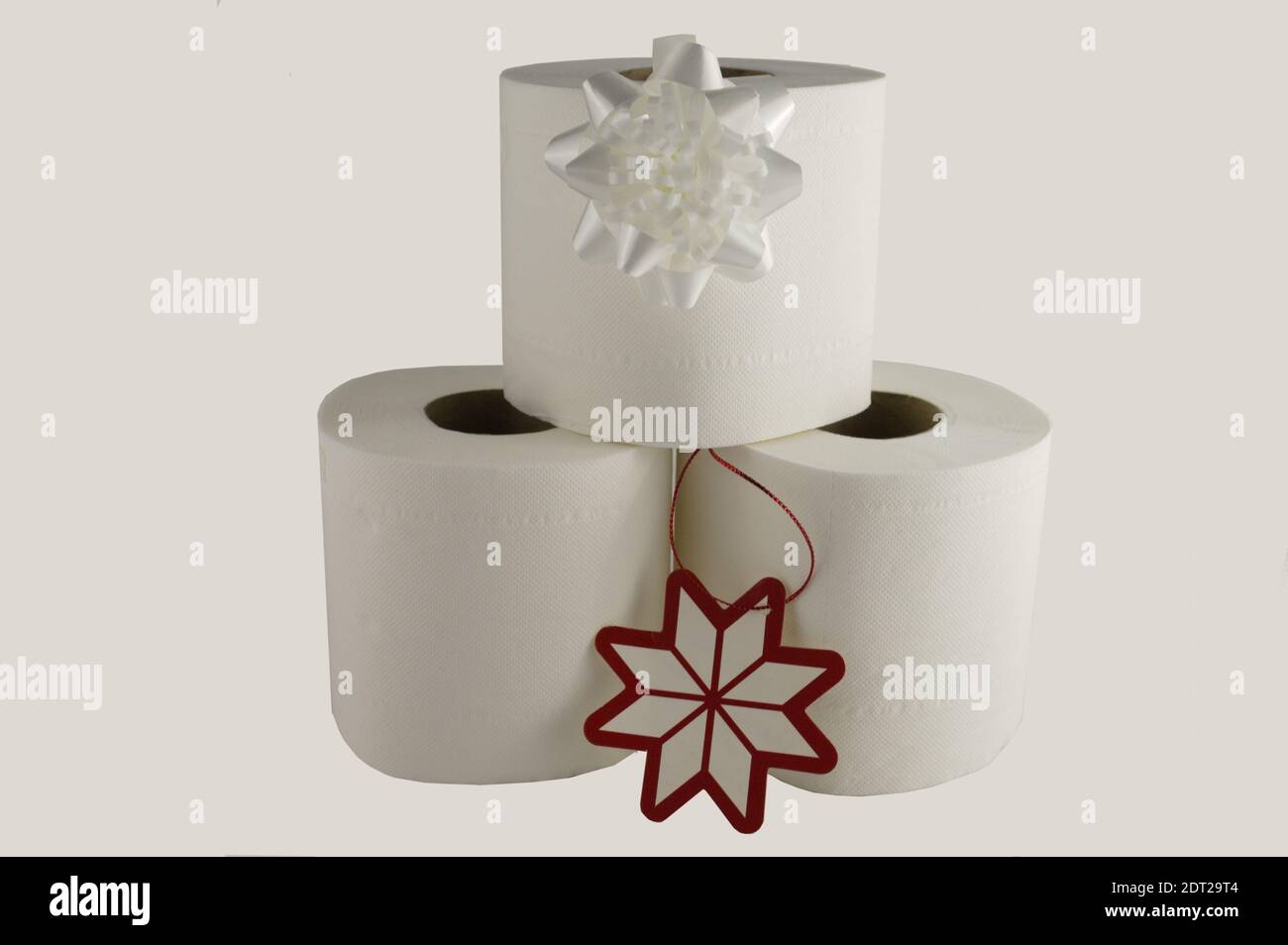 Three white toilet rolls with a white bow and red and white gift tag, practical gifts concept Stock Photo