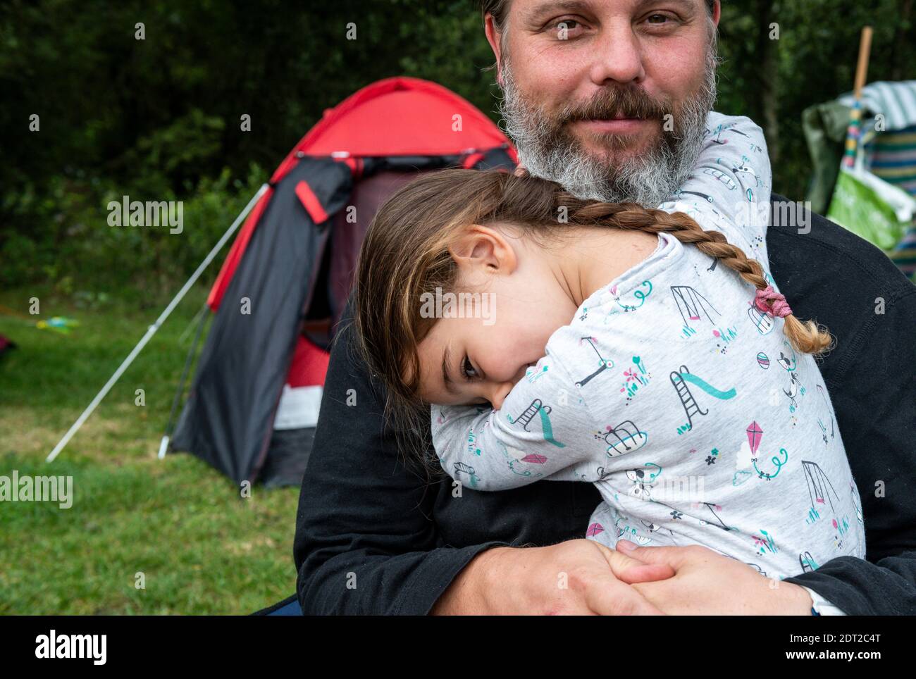 Father hugging daughter at camp site Stock Photo