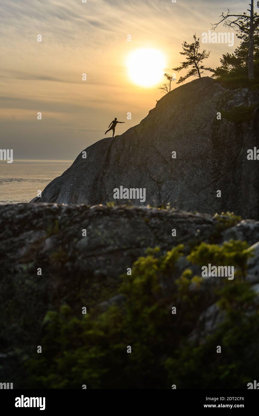 Silhouette of man standing on one leg on cliff, Ontario, Canada Stock Photo