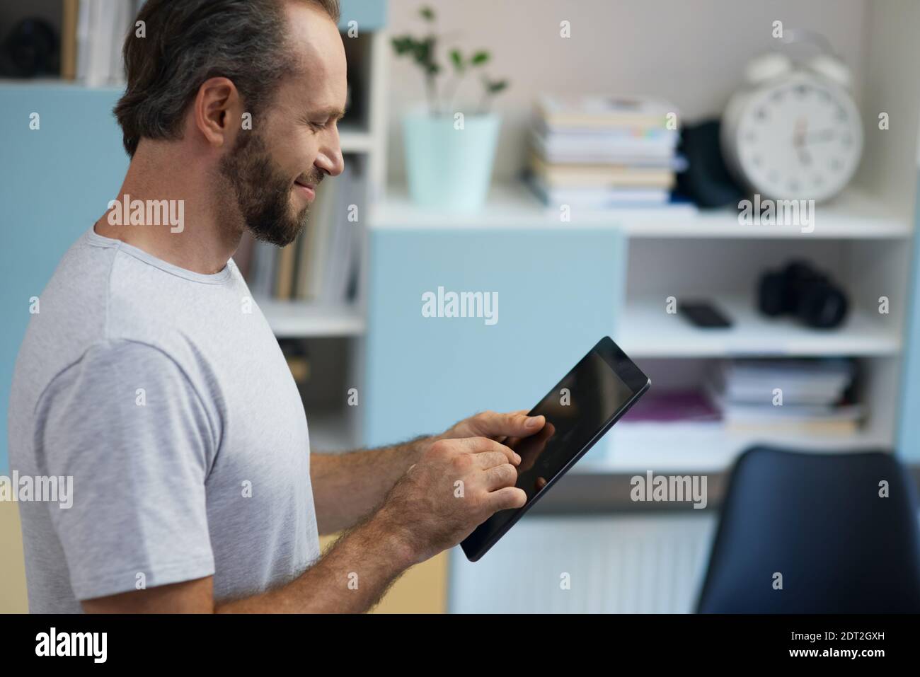 Professional repairman looking cheerful while using digital tablet, standing indoors Stock Photo