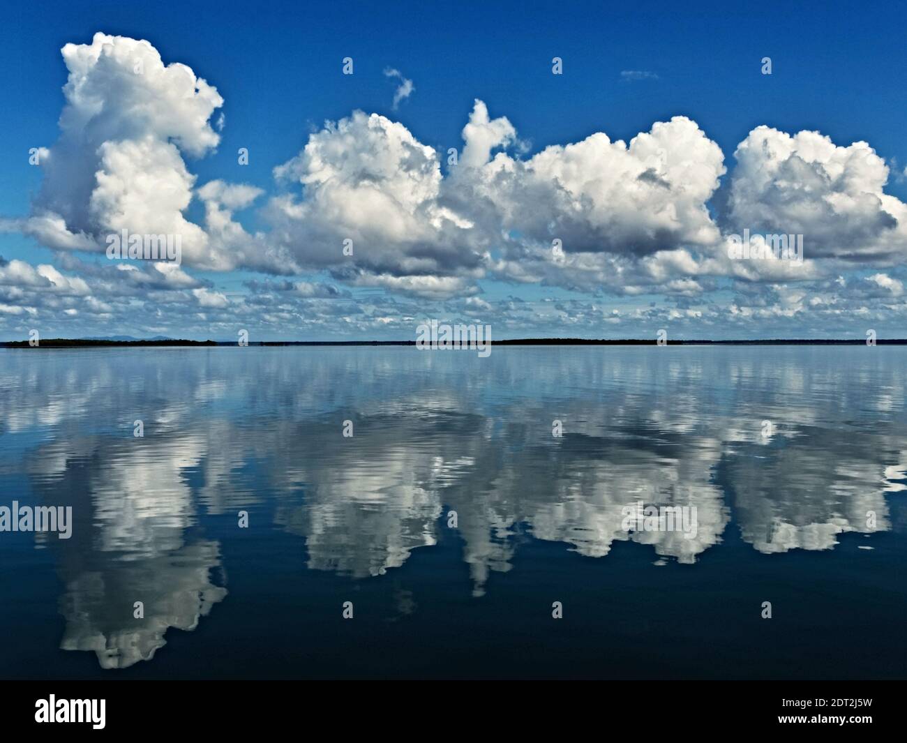 This very crisp colorful cloud scene with blue  sky and water reflections was captured in the sea between Fraser Island and the Australian mainland.    cloud, clouds, reflections, water, sea, ocean, panorama, cloudy, scene, scenic, view, bright clouds, blue sky, coast, coastal, sky art, skyscape, colour, color, colourful, blue, white, cloudscape, daylight, sunlight, nature, air, atmosphere, weather, heaven, beauty in nature , stock image, images, royalty free photo, stock photos, stock photograph,  picture,  graphic, background, Fraser island, Queensland, Australia, Geoff Childs, sunypicsozcom Stock Photo