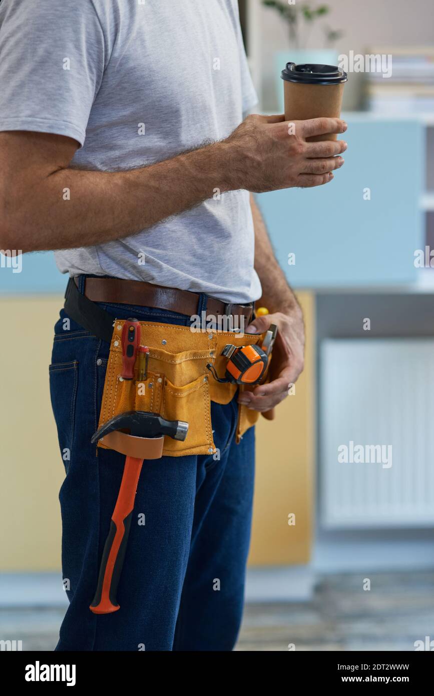Coffee break. Cropped shot of professional repairman wearing a tool