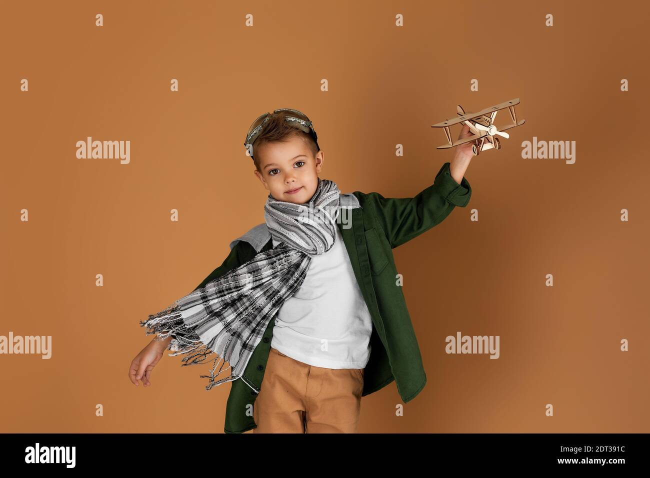 happy child boy playing with wooden toy airplane on studio background ...